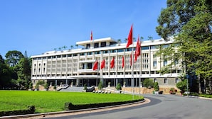A large building with multiple red flags, a well-maintained lawn, and a curved driveway. - Chotel Ben Thanh (Ho Chi Minh City)