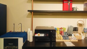 A kitchen area with a microwave, stacked cups, and a coffee machine. - Chotel Ben Thanh (Ho Chi Minh City)