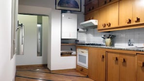 A kitchen with wooden cabinets, a white refrigerator, a stove, and a sink. - Macci Number Eight (Florence)