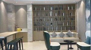 Ein modernes Interieur mit einer Couch, Sesseln, einem kleinen Tisch und einem Bücherregal voller dekorativer Gegenstände.