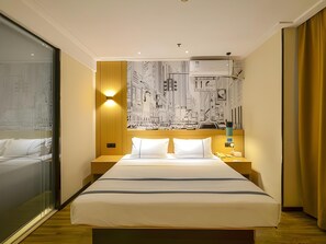 Ein Hotelzimmer mit einem großen Bett, einem Stadtbild-Wandgemälde, einem Nachttisch und einem Beistelltisch.