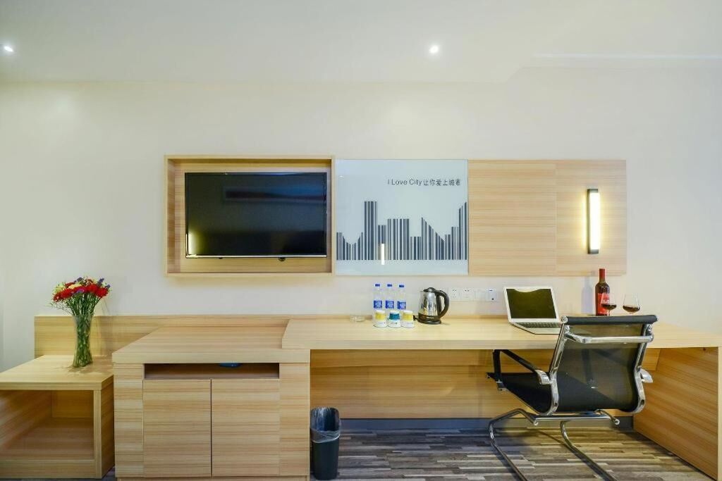 Un espace de bureau moderne comprenant un bureau en bois, une chaise, un téléviseur, une affiche et une poubelle.