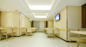 Uma sala de conferências com mesas e cadeiras, uma TV de tela plana na parede e um teto com iluminação embutida.
