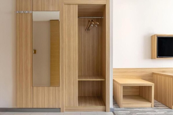 A wooden wardrobe with a mirror, a coat rack, and a flat-screen TV mounted on the wall. - City Comfort Inn (Chongqing)