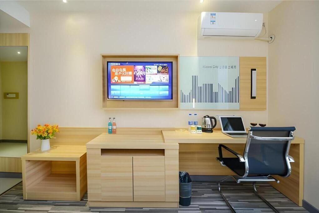 A modern reception desk with a flat-screen TV, a coffee machine, and a laptop.