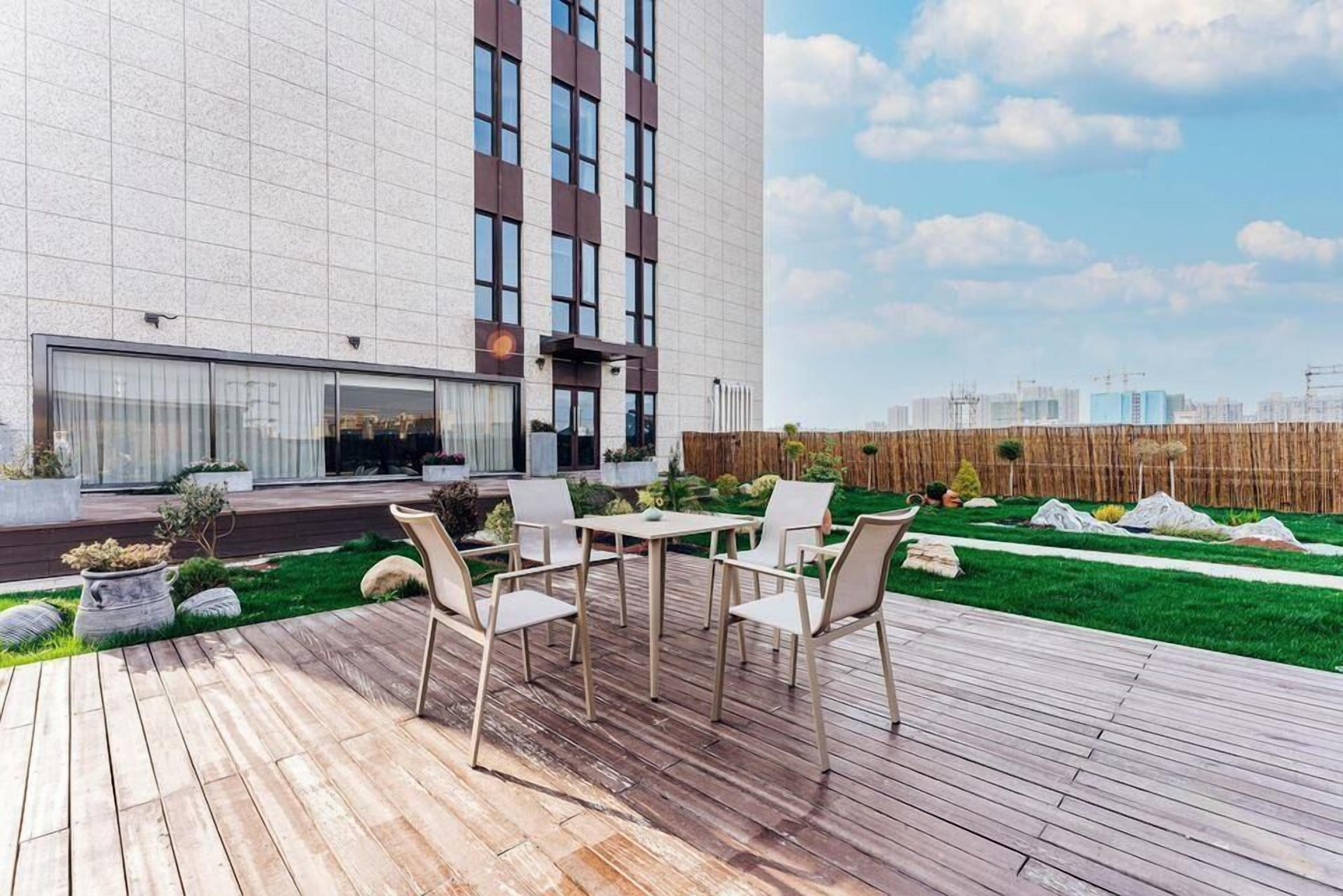 A modern outdoor patio with a wooden deck, a table, and chairs.