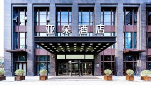 A modern hotel entrance with a covered entrance, large windows, and potted plants. - Atour Hotel Haifeng Road Haiyan Jiaxing (Jiaxing)
