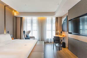 A hotel room with a bed, a desk, a chair, a TV, and a large window with curtains. - Atour Hotel Haifeng Road Haiyan Jiaxing (Jiaxing)