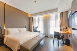 Una habitación de hotel moderna con una cama grande, un escritorio y una silla.