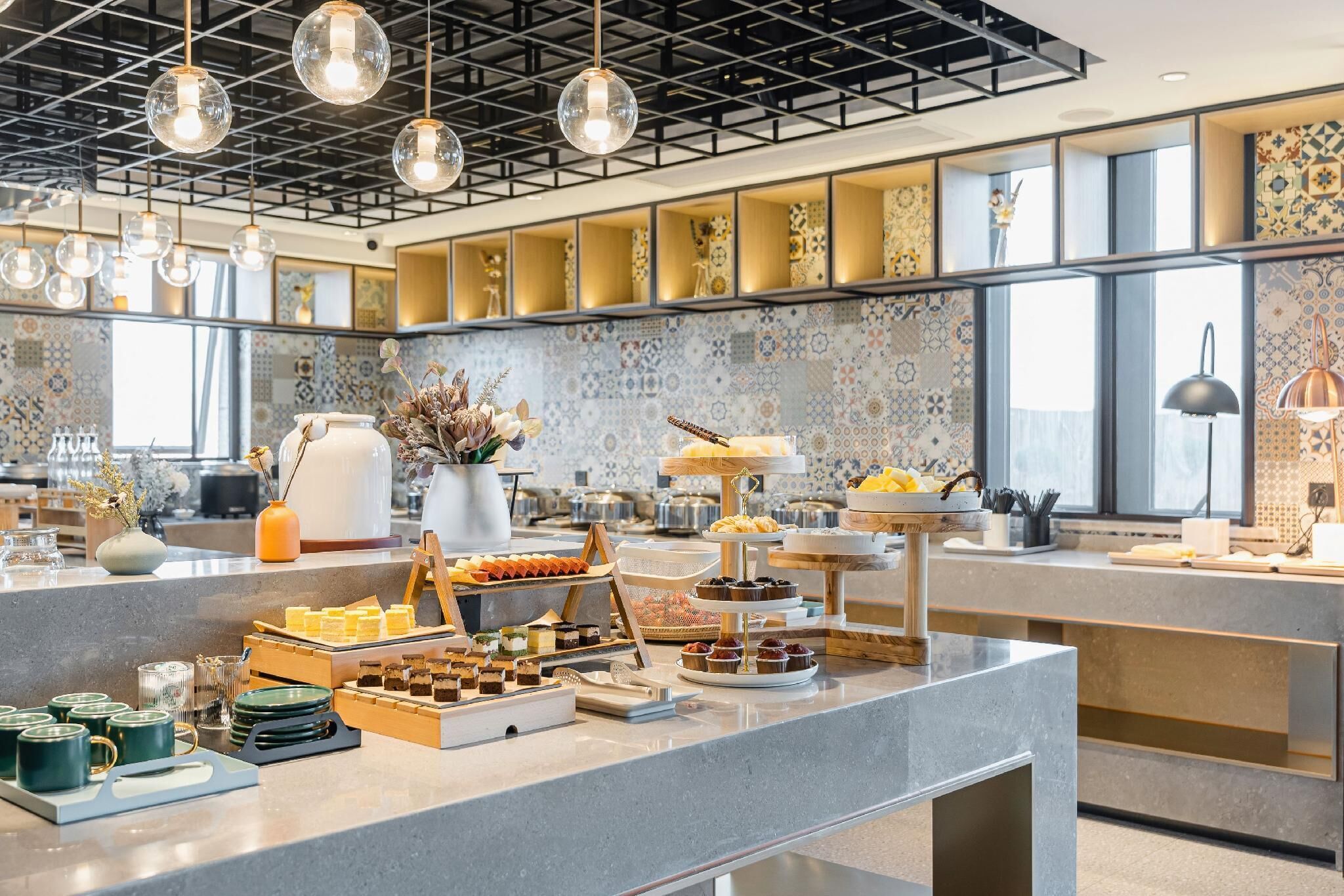 A buffet area with various food items and a modern kitchen in the background.