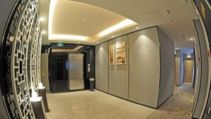 A hallway with a modern design, featuring a curved ceiling, a wall-mounted elevator, and a trash bin. - Shangyuan Hotel (Guangzhou)
