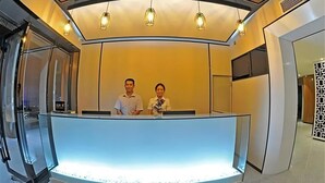 A reception area with a curved counter, two staff members, and a modern interior design. - Shangyuan Hotel (Guangzhou)