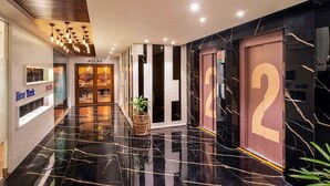 A modern hotel lobby with a polished black marble floor, a reception desk, and a large number '2' sign.