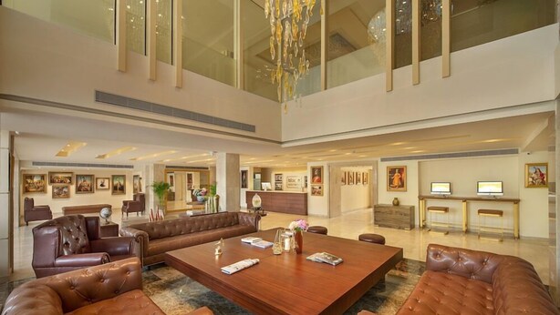A spacious lobby with a large wooden coffee table, leather sofas, and artwork on the walls.