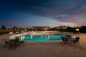 A pool area with lounge chairs and tables, surrounded by a paved deck. - HDB Al Khobar Resort and Spa (Al Khobar)