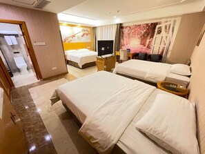 Ein Hotelzimmer mit zwei Betten, einem Fernseher, einem Schreibtisch und einem durch eine offene Tür einsehbarer Badezimmer.