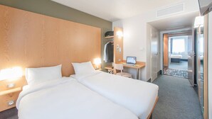 A hotel room with two beds, a desk with a laptop, a mirror, and a wardrobe. - B&B Hotel Ales Pole Mecanique (Saint-Martin-de-Valgalgues)