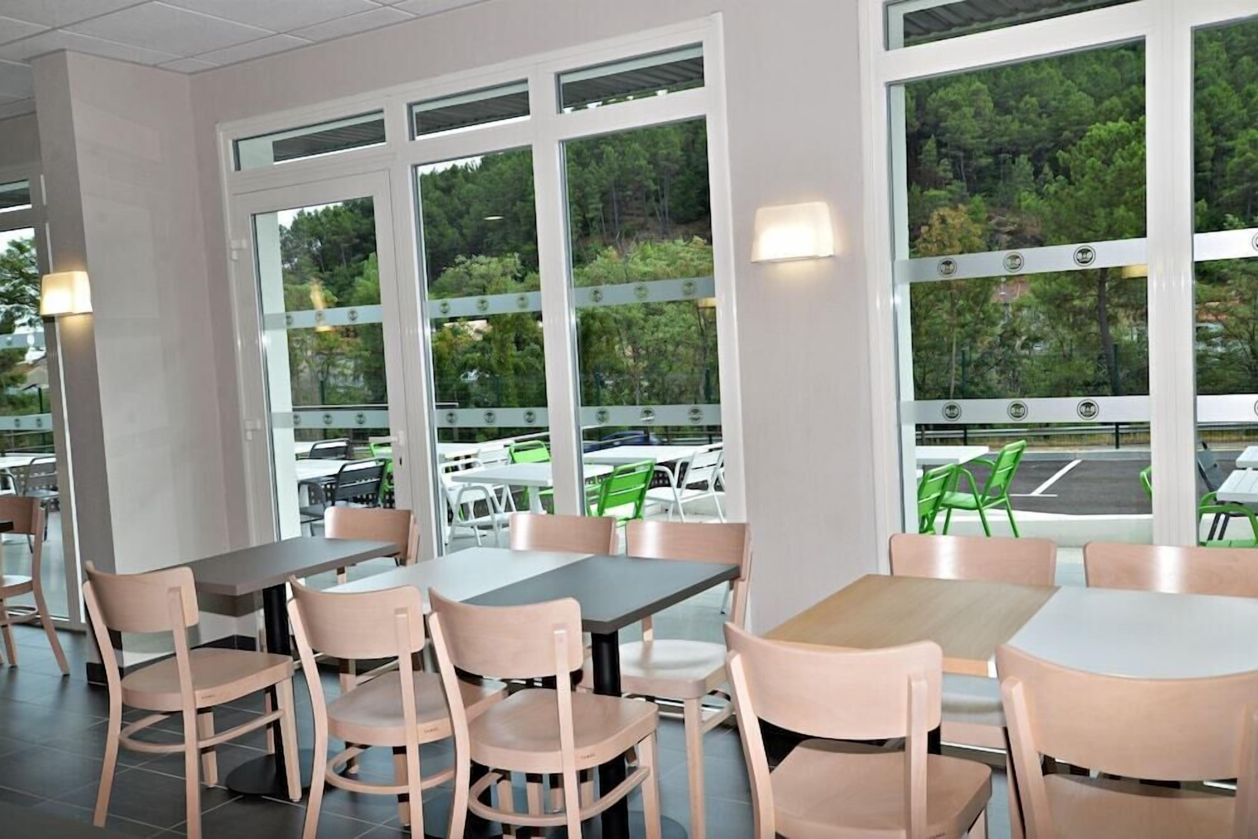 A restaurant with large windows, wooden tables, and chairs.