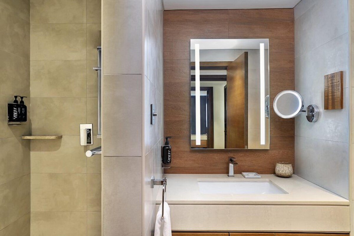 A modern bathroom with a large mirror, a sink, and a shower area.