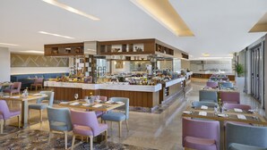 A modern restaurant with a central bar, multiple dining areas, and a kitchen in the background. - Dusitd2 Naseem Resort Jabal Akhdar (Sayq)