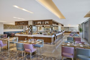 A modern restaurant with a central bar, multiple dining areas, and a kitchen in the background. - Dusitd2 Naseem Resort Jabal Akhdar (Sayq)