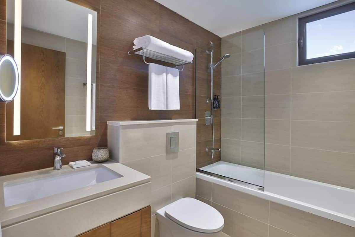A modern bathroom with a large mirror, a sink, a toilet, and a glass-enclosed shower.