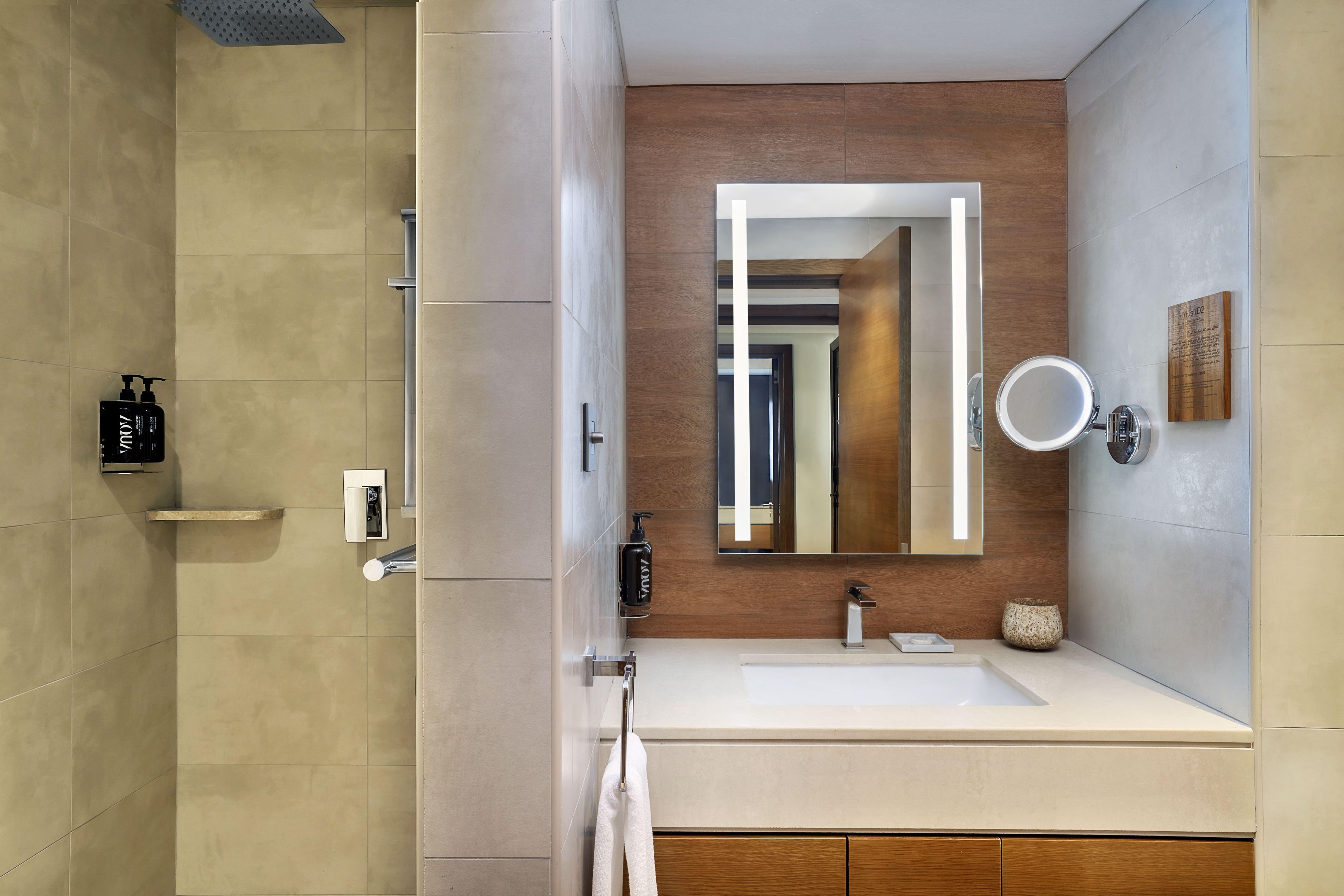 Une salle de bain moderne avec un grand miroir, un lavabo et un espace douche.