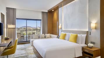 Une chambre d’hôtel avec un grand lit, un bureau, une chaise et une vue sur le paysage désertique.