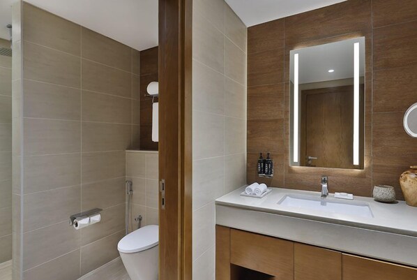 Un baño moderno con ducha, inodoro, tocador y un espejo grande.