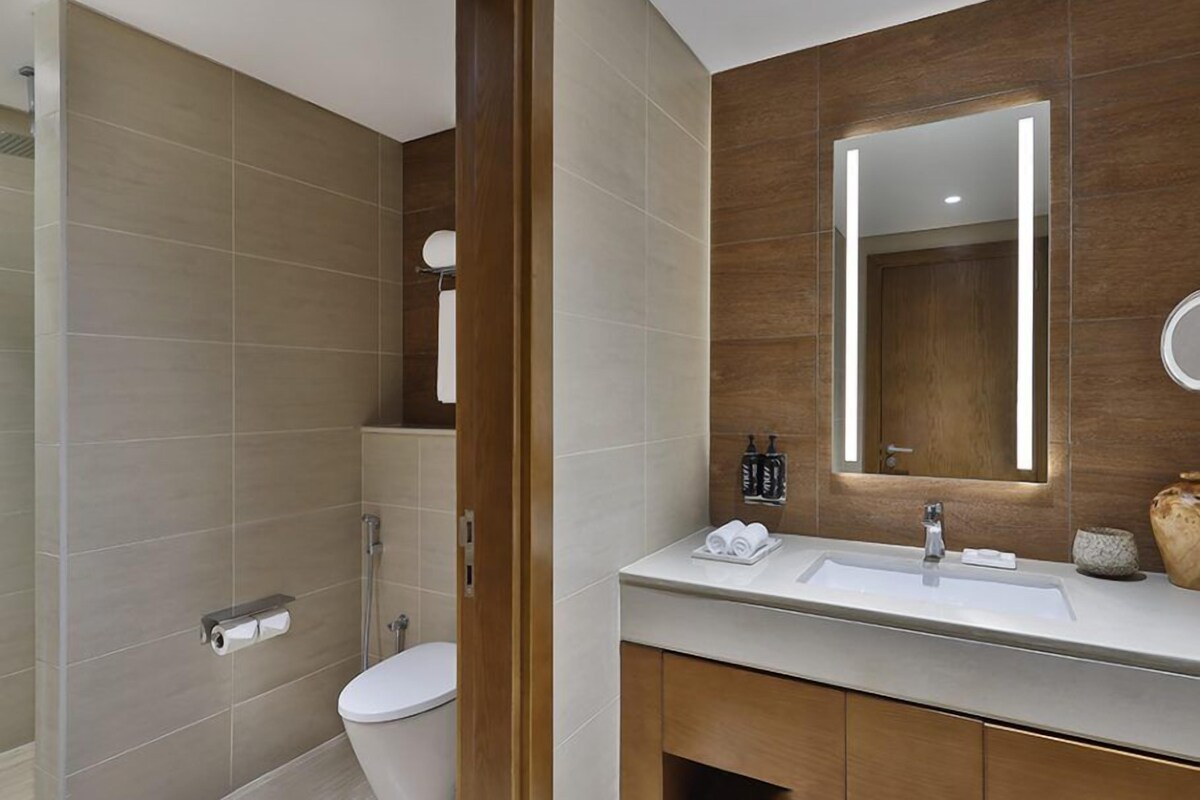 A modern bathroom with a shower, toilet, vanity, and a large mirror.