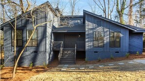 Une maison moderne à deux étages, dotée d’un porche à l’avant, d’un escalier menant à l’entrée et d’une cour bien entretenue.