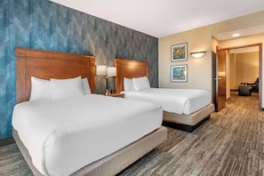 A hotel room with two beds, a wooden headboard, a nightstand with a lamp, and a painting on the wall. - Drury Inn and Suites Valdosta (Valdosta)