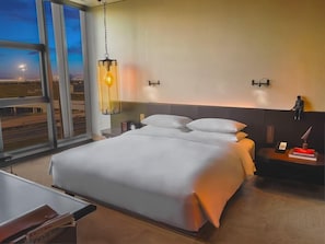 A modern hotel room with a large bed, a bedside table, a nightstand, a lamp, and a view of the cityscape through the window. - Mumian Hotel Beijing Daxing Airport (Daxing)