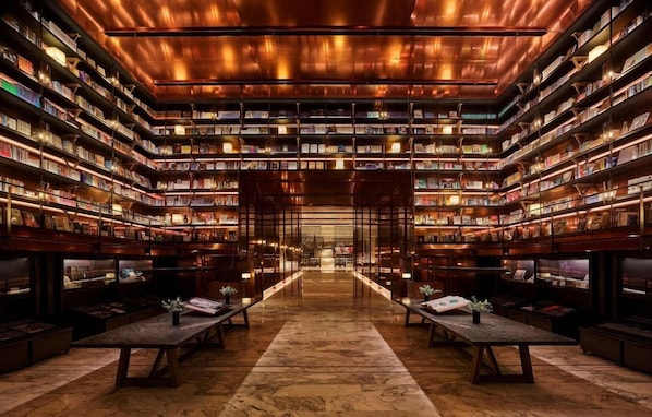 A library with bookshelves on all sides, a central aisle, and tables with plants. - Mumian Hotel Beijing Daxing Airport (Daxing)