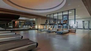 Ein geräumiges Fitnessstudio mit mehreren Laufbändern, einer Spiegelwand und verschiedenen Trainingsgeräten.