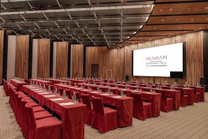 A conference room with rows of tables and chairs, a large screen displaying 'MUMIAN' branding, and a wooden panel wall. - Mumian Hotel Beijing Daxing Airport (Daxing)