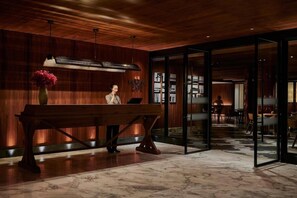 A reception area with a wooden desk, a vase of flowers, and a modern interior design. - Mumian Hotel Beijing Daxing Airport (Daxing)