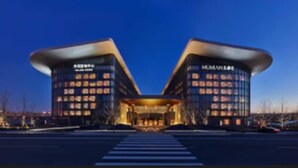 Ein modernes Hotel mit symmetrischer Fassade, gekennzeichnet durch zwei markante Türme mit beleuchteten Fenstern und einem zentralen Eingang.
