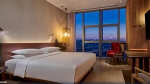 Ein Hotelzimmer mit einem großen Bett, einem Schreibtisch, einem Sessel und einem Fernseher.