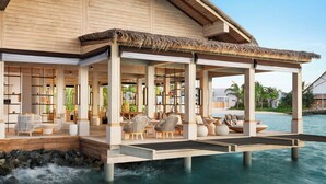 A beachfront resort with a covered outdoor seating area, a pool, and a view of the ocean.