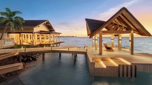 A waterfront hotel with overwater bungalows, a wooden deck, and a pool.
