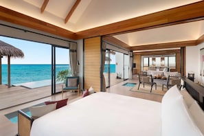 Een ruime slaapkamer met een groot bed, een zithoek met een tafel en uitzicht op zee.