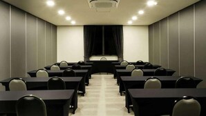 A conference room with a long table, chairs, a projector screen, and a ceiling-mounted air conditioning unit. - Vila Gale Alagoas (Barra de Santo Antonio)
