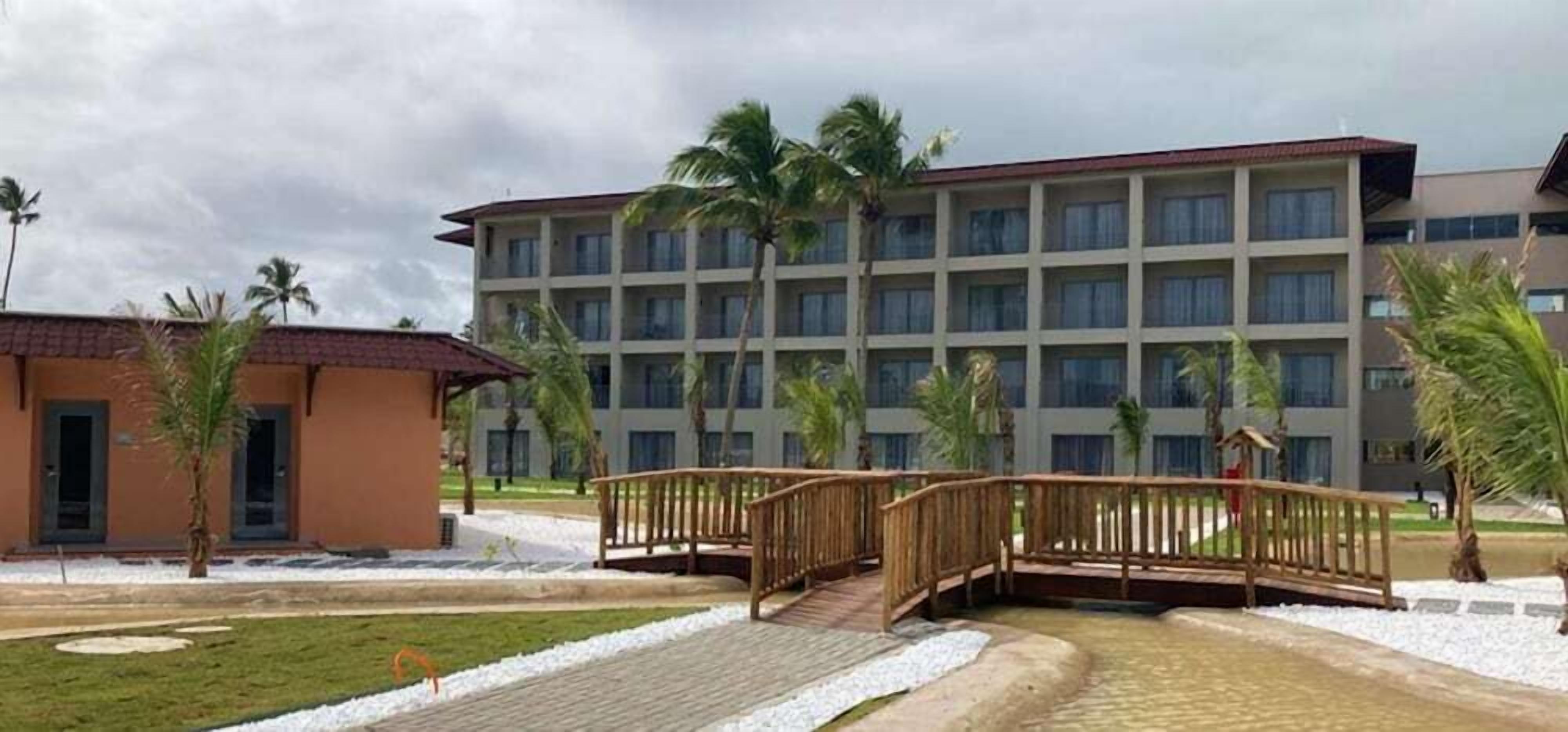 Um hotel com um pátio central, palmeiras e uma ponte.