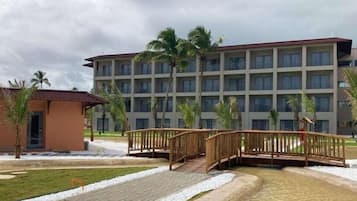Um hotel com um pátio central, palmeiras e uma ponte.
