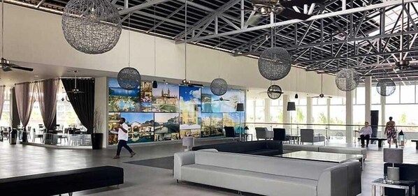 A spacious lobby with a high ceiling, large windows, and a modern chandelier. - Vila Gale Alagoas (Barra de Santo Antonio)
