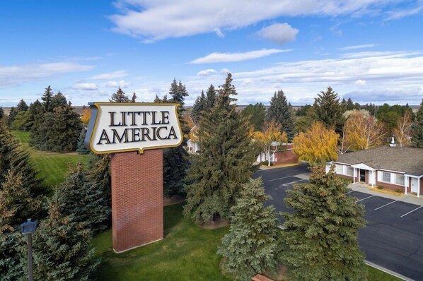 Opastekyltti, jossa lukee ”Little America”, ja etualalla näkyy tiilestä rakennettu rakennus ja parkkipaikka.