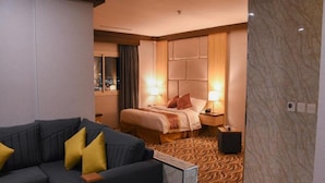 A hotel room with a bed, bedside tables, a sofa, and a patterned carpet. - Florida Inn Najran (Nejran)