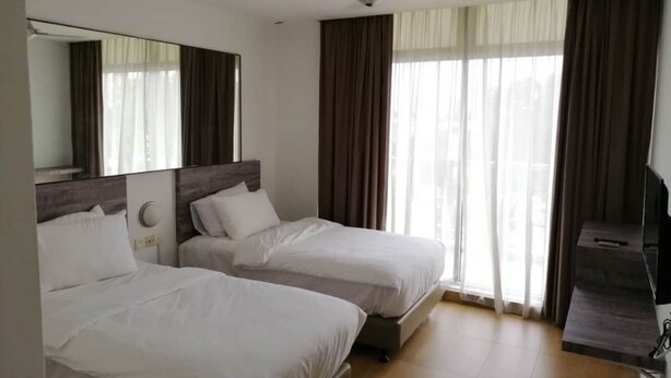 Ein Hotelzimmer mit zwei Betten, einem Fernseher und einem großen Fenster mit Vorhängen.