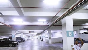 Eine Parkgarage mit mehreren Ebenen, Betonpfeilern und ausgewiesenen Parkplätzen.